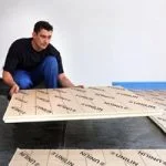 Man brengt vloerisolatie aan op nieuwe betonvloer